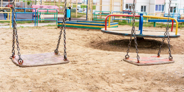 istock wooden swings on rusty chains and carousel on playground 1289222560