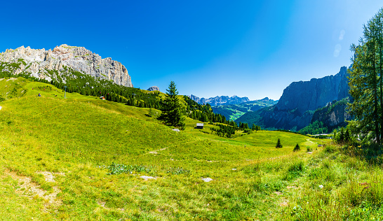 Italian mountains near the Langkofel Group, and green meadows on a sunny cloudless day. High resolution panorama.
