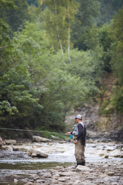 istock Mature man using rod for catching fish in mountain river 1289223495