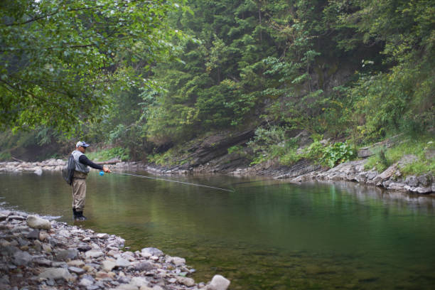 istock Man throwing fishing rod into mountain river 1289223982