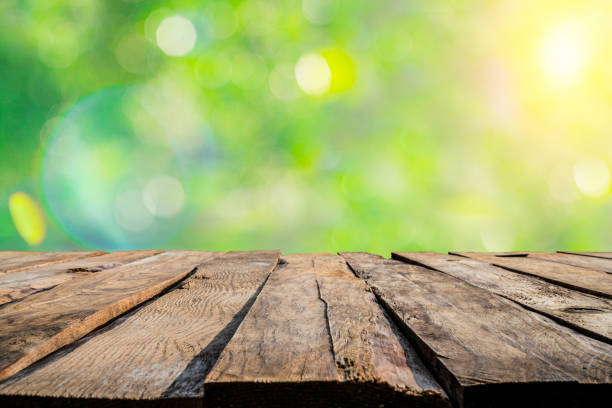 Empty rustic wooden table with defocused yellowish lush foliage at background. Ideal for product display on top of the table. Predominant colors are green, yellow and brown. XXXL 42Mp outdoors photo taken with SONY A7rII and Zeiss Batis 40mm F2.0 CF