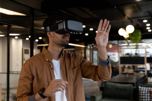 istock Mixed race businessman wearing virtual reality headset in creative office 1289225583