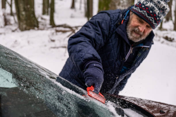 istock Senior man cleaning the ice down the windshield from the snowy car 1289226367