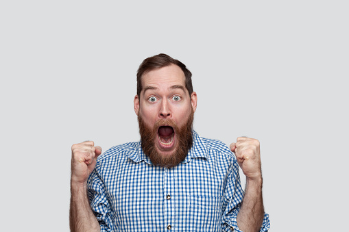 Portrait of a bearded man with mouth open shaking fists in the winning gesture