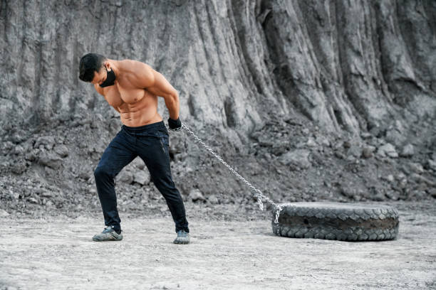 istock Muscular man in mask exercising outdoors with tyres 1289228158
