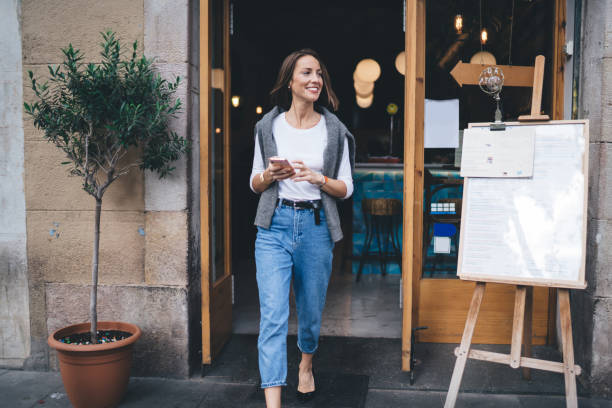 istock Smiling woman with smartphone leaving cafe 1289230919