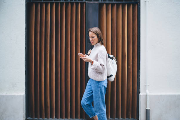 istock Pensive lady checking news on smartphone while walking outside 1289230934