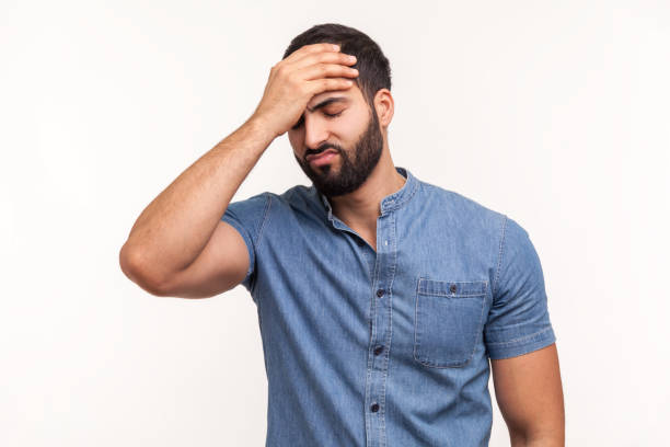 Upset frustrated man holding forehead with hand, making facepalm gesture, lost all his money, forget about date, big failure Upset frustrated man holding forehead with hand, making facepalm gesture, lost all his money, forget about date, big failure. Indoor studio shot isolated on white background defeat stock pictures, royalty-free photos & images