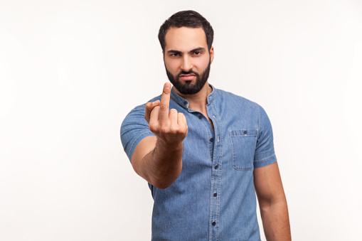 Impolite aggressive man showing middle finger and asking to get off looking at camera with negativity, disrespectful behaviour. Indoor studio shot isolated on white background