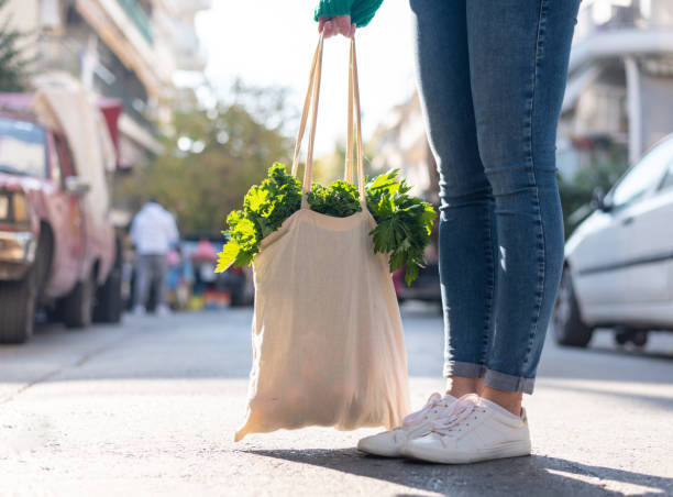 vista ad angolo basso al femminile con borsa della spesa riutilizzabile con verdure all'interno. stile di vita ecologico - recycled bag foto e immagini stock