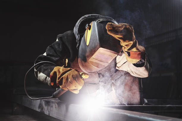 Male in face mask welds with welding Male in face mask, protective gloves welds with welding. Welder makes weld seam on metal frame. Worker dressed in protective clothes. welding mask stock pictures, royalty-free photos & images