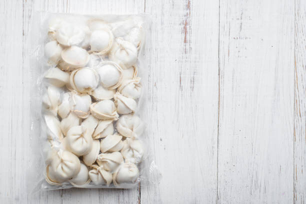frozen dumplings in packaging on a white wooden background.