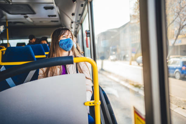 istock Woman with mask in bus transport looking through window 1289244455