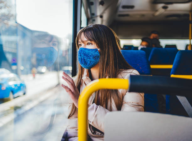 istock Woman with mask in bus transport looking through window 1289247927
