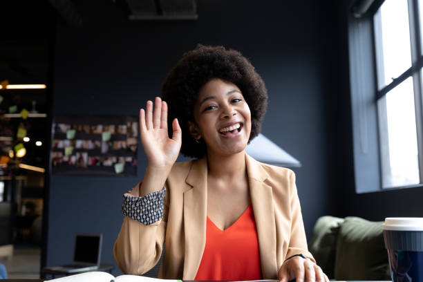 istock Smiling mixed race businesswoman during video call in creative office, waving 1289248607