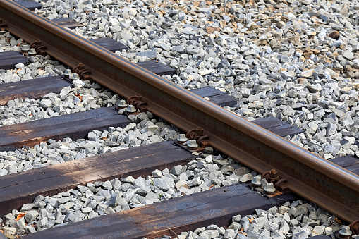 Single rail as a part of railroad. Wooden sleepers and gravel are seen as well.