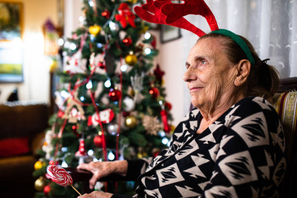 istock A happy old woman sitting next to a Christmas tree 1289253847