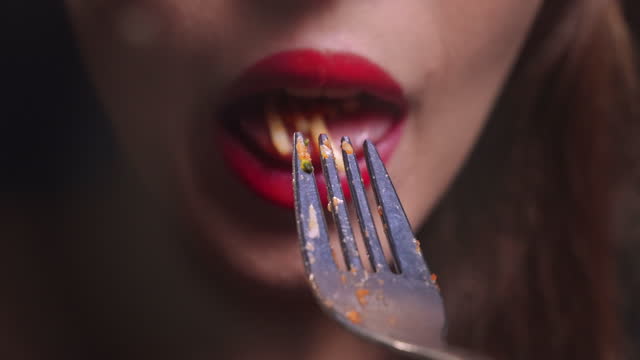 Young woman mouth eating spaghetti pasta bolognese on a silver fork