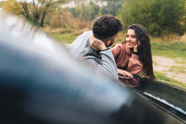 istock Beautiful young couple having fun talking leaning on car 1289256159