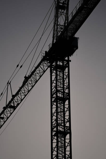 istock Silhouette of a construction crane on gray sky background 1289256851