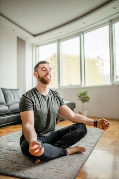 istock Young smiling man practicing yoga, doing Padmasana exercise, Lotus pose, working out, wearing sportswear at home 1289259334