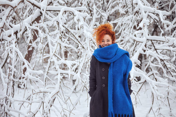 Young beautiful woman in warm clothing enjoying outdoors while walking in the winter forest
