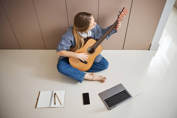istock Talented young woman playing guitar at home 1289261935