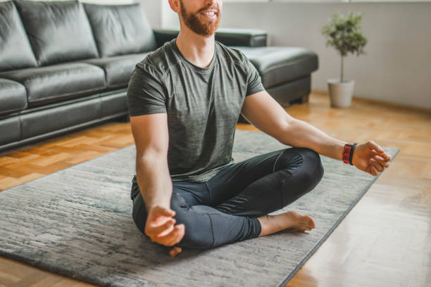 istock Close up of young smiling man practicing yoga, doing Padmasana exercise, Lotus pose, working out, wearing sportswear at home 1289263185