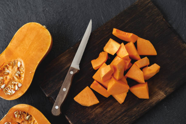 istock Cut pieces of raw pumpkin on wooden board on table 1289263321