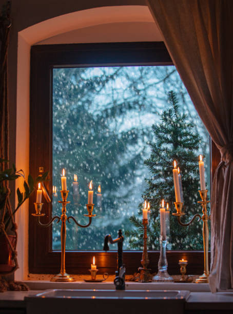 istock candles on the window in kitchen during a snowfall, trees on the background 1289267528