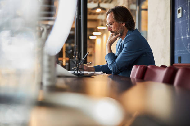 istock Thoughtful gentleman with a pencil sitting at the desk 1289272058
