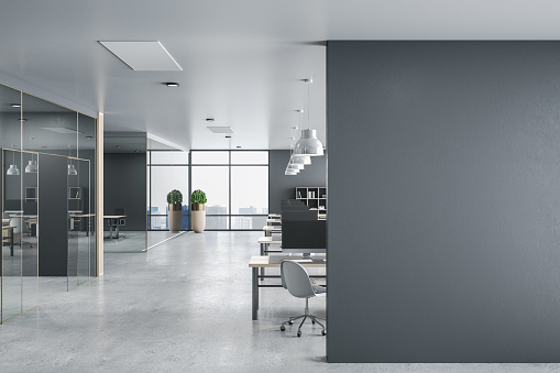 Comfortable office hall with computers on table and blank gray wall.  Workplace and corporate concept. 3D Rendering