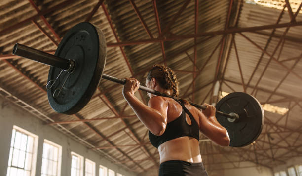 istock Strong woman exercising with barbell 1289275436
