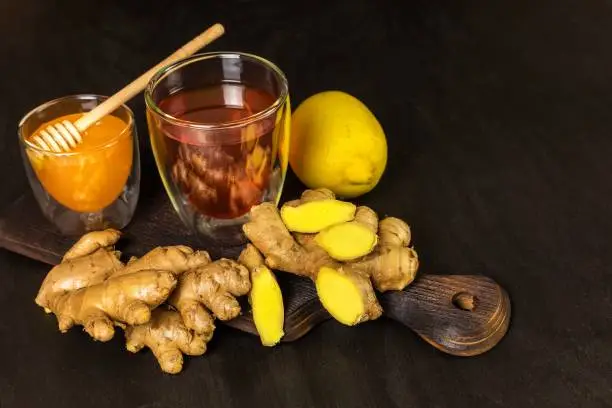 Ginger tea in a cup on black wooden background. Treatment of flu and colds. Healthy tea.