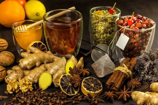 Ginger tea in a cup on black wooden background. Cinnamon and star anise with cloves. Treatment of flu and colds. Herbal medicinal tea.