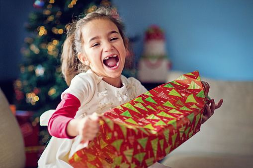 Happy girl is opening her Christmas gift