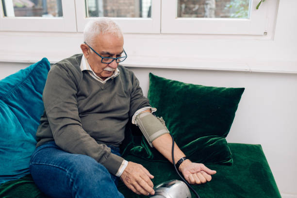 старший человек измерения кровяного давления - blood pressure gauge surveillance home interior house стоковые фото и изображения