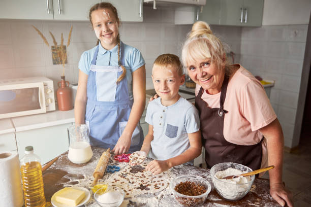 happy children and their cute grandma standing in kitchen - chef trainee cooking teenager imagens e fotografias de stock