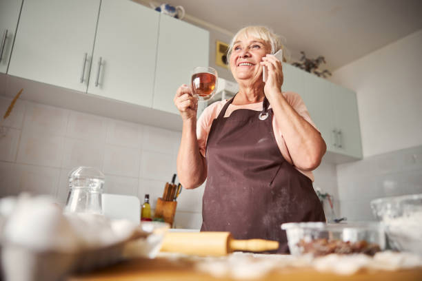 istock Pleased eldelry woman having conversation over phone at home 1289283777