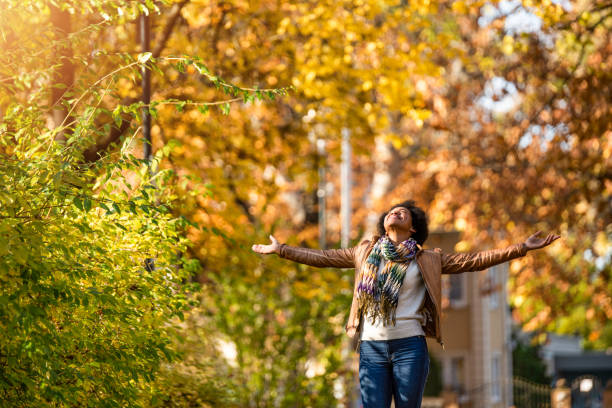 African American woman day dreaming in public park on beautiful autumn day. stock photo