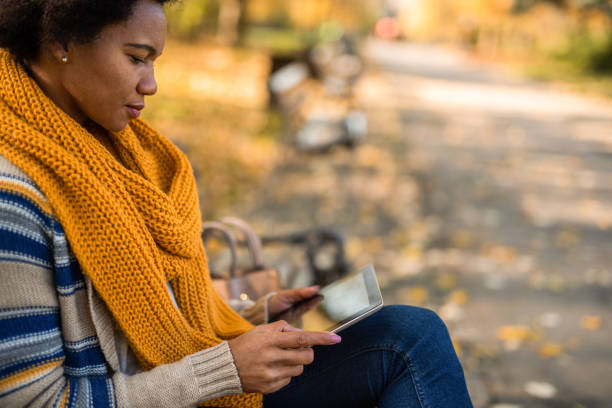 istock African American woman using digital tablet in the public park. 1289286528