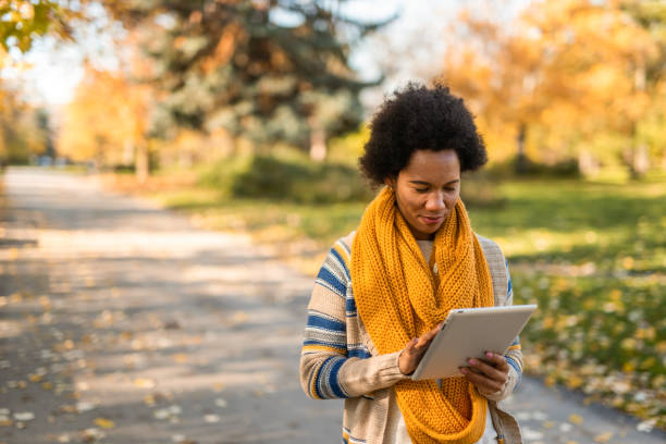 istock Young African American woman using digital tablet in the public park. 1289287049
