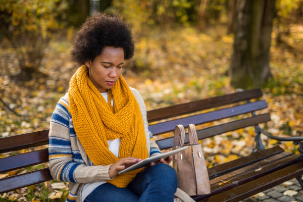 istock African American woman using digital tablet in the public park. 1289287091
