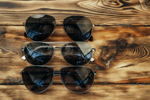 набор темных солнцезащитных очков на коричневой деревянной поверхности - sunglasses wood black dark стоковые фото и изображения