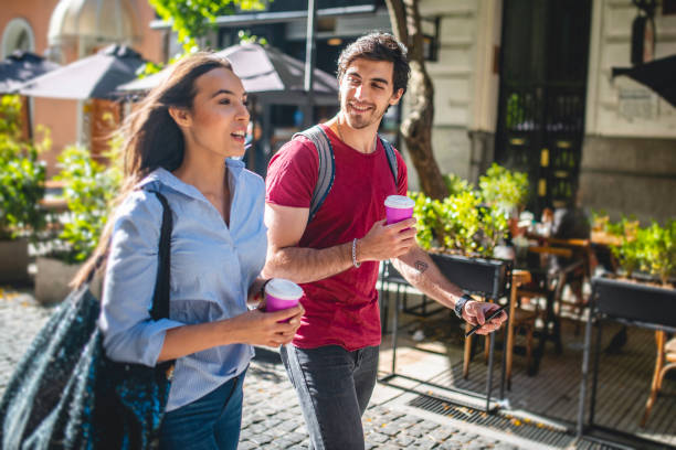 istock Vacationing Couple Walking with Coffee and Smart Phone 1289288936