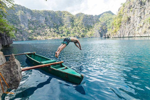 Young adult man diving off boat while traveling in the Philippines stock photo