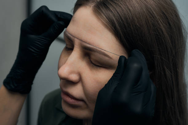 istock Permanent eyebrow makeup procedure. Eyebrow tattooing, process. The use of tools by a master for permanent eyebrow makeup. 1289288994