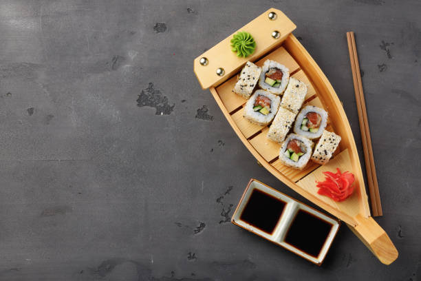 istock Sushi roll served on wooden boat plate on black background 1289289530