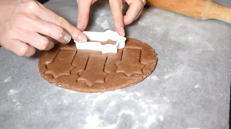 a woman making Christmas star shape cookies from gingerbread dough