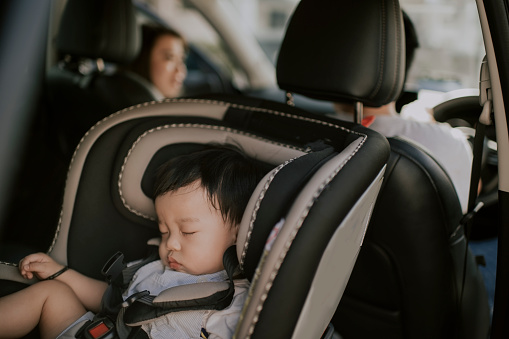 asian chinese baby boy sleeping in baby seat back seat of car during outing with his parent